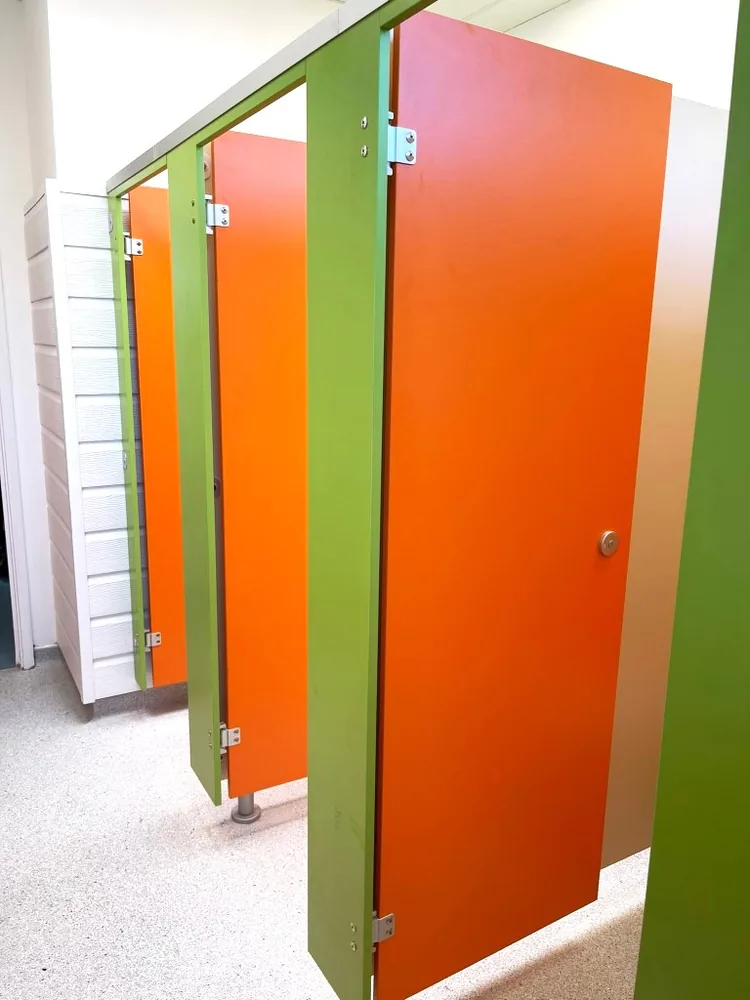 Volante toilet cubicles with woodgrain doors in a commercial washroom